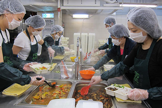 来自社会各界的义工在惜食堂厨房分装食物